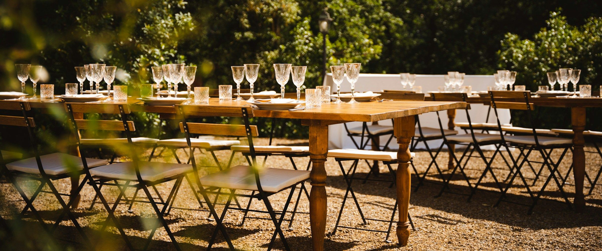 Long wooden tables set for a shared meal in a sunlit garden